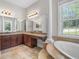 Luxurious bathroom featuring a large soaking tub with tile surround, dual vanities, and natural light at 10110 Weeks Dr, Brooksville, FL 34601