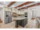 Gourmet kitchen featuring an island, stone floors, stainless steel appliances, and wooden beams at 10110 Weeks Dr, Brooksville, FL 34601
