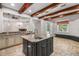Open concept kitchen with granite counters, central island, stainless appliances, and decorative wood ceiling beams at 10110 Weeks Dr, Brooksville, FL 34601