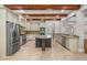 Spacious kitchen featuring travertine floors, stainless steel appliances, granite countertops, and wooden beams at 10110 Weeks Dr, Brooksville, FL 34601