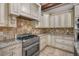 Gourmet kitchen with custom cabinetry, stone backsplash, granite countertops, and stainless steel appliances at 10110 Weeks Dr, Brooksville, FL 34601