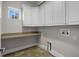 Laundry room with white cabinets, beige countertop, tile flooring, and window at 10110 Weeks Dr, Brooksville, FL 34601
