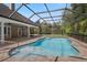 Backyard pool in screened enclosure, with brick paver surround and view of trees at 10110 Weeks Dr, Brooksville, FL 34601