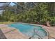 In-ground pool with screened enclosure, brick paver surround, and seating area at 10110 Weeks Dr, Brooksville, FL 34601