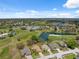 Beautiful aerial view of a golf course community with homes, a pond with a fountain, and a clubhouse with a pool at 11631 Wayside Willow Ct, Hudson, FL 34667