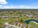 Beautiful aerial view of a golf course community with homes, a pond with a fountain, and a clubhouse with a pool at 11631 Wayside Willow Ct, Hudson, FL 34667