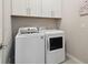 Functional laundry room with white washer and dryer, and upper cabinets at 12272 Rangeland Blvd, Odessa, FL 33556