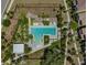 An aerial view of a community pool featuring a sun deck with lounge chairs, surrounded by manicured landscaping and greenery at 12272 Rangeland Blvd, Odessa, FL 33556
