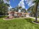 Charming one-story home enhanced with mature landscaping, a bright red door, and a two-car garage at 1280 Thornton Ct, Spring Hill, FL 34608