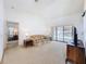 Bright living room with neutral carpet, sofa, side tables, and sliding doors leading to the pool area at 1280 Thornton Ct, Spring Hill, FL 34608