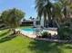 Backyard with pool, patio furniture, tropical plants, flowers, landscaped garden, and lawn at 1412 Linstock Dr, Holiday, FL 34690