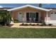 Inviting front of the home with manicured lawn, walkway leading to the entrance and quaint front seating area at 1412 Linstock Dr, Holiday, FL 34690