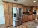 Modern kitchen with stainless steel refrigerator, wood cabinets, and tile flooring at 1412 Linstock Dr, Holiday, FL 34690