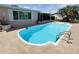 Backyard pool with tile patio, featuring view of porch, landscaped garden, and well-maintained lawn at 1412 Linstock Dr, Holiday, FL 34690