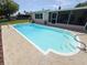 Backyard pool features steps; beyond are the screened-in porch, patio, landscaping, and lawn at 1412 Linstock Dr, Holiday, FL 34690
