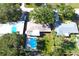 Aerial view of a home featuring a backyard pool, patio with chairs, mature trees, and grassy lawn at 1540 Lime St, Clearwater, FL 33756
