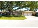Charming single story home featuring a mature shade tree, green grass, and a two car garage at 1540 Lime St, Clearwater, FL 33756