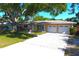 Charming single story home featuring a mature shade tree, green grass, and a two car garage at 1540 Lime St, Clearwater, FL 33756