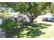 Charming single story home featuring a mature shade tree, green grass, and a two car garage at 1540 Lime St, Clearwater, FL 33756