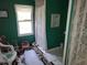 Simple bathroom with green walls, patterned rugs, and natural light from the window at 18255 Lake Lindsey Rd, Brooksville, FL 34601