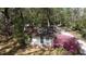 Charming white cottage with blooming pink azaleas and a natural setting with mature trees at 18255 Lake Lindsey Rd, Brooksville, FL 34601