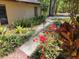 Tan house featuring lush landscaping, colorful flowers, and a sidewalk leading to the entrance at 18255 Lake Lindsey Rd, Brooksville, FL 34601