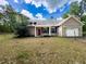 Front exterior features red door, white columns, and 2-car garage perfect for a starter home, set in a lovely yard at 18308 Valor Path, Brooksville, FL 34604