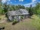 Aerial view highlighting a charming home with a screened lanai, lush greenery, and a well-maintained yard under a partly cloudy sky at 18308 Valor Path, Brooksville, FL 34604