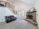 Living room featuring a stone fireplace, carpeted floor, and stairs with wrought iron railings at 18308 Valor Path, Brooksville, FL 34604