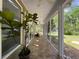 Covered porch with tiled floor, ceiling fans and natural light, overlooking a lush backyard with plants at 18308 Valor Path, Brooksville, FL 34604