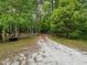 Secluded property entrance featuring a gate flanked by dense trees, offering privacy and leading to a serene, natural setting at 18308 Valor Path, Brooksville, FL 34604