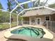 This in-ground spa with water features is surrounded by a safety fence and is set in an enclosed outdoor area at 18308 Valor Path, Brooksville, FL 34604
