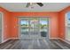 A living room with wood floors, orange walls, and a sliding glass door leading to an outdoor area with a fire pit at 3362 Minnow Creek Dr, Hernando Beach, FL 34607