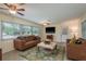 Comfortable living room with a ceiling fan, brown couches, an area rug, and a view of the front yard at 37623 Florida Ave, Dade City, FL 33525