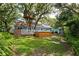 Green backyard with mature trees, a treehouse, a hot tub, and a manicured lawn at 417 Inness Dr, Tarpon Springs, FL 34689