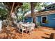Wood deck with dining table and chairs, leading to a blue home with mature trees and yard at 417 Inness Dr, Tarpon Springs, FL 34689
