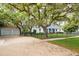 Home nestled among mature trees with a brick driveway and a fenced front yard at 417 Inness Dr, Tarpon Springs, FL 34689