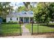 Charming cottage-style home with a well-manicured lawn, dark metal fence, and lush landscaping at 417 Inness Dr, Tarpon Springs, FL 34689
