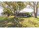 Exterior view of home's backyard featuring a spacious yard, a screened patio, and mature trees at 4647 Gazebo Ct, New Port Richey, FL 34655