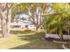 View of home's backyard featuring mature trees, lush landscaping, and a charming swing at 4647 Gazebo Ct, New Port Richey, FL 34655