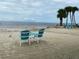 A sandy beach scene with outdoor seating, palm trees, and views of the ocean for relaxation and enjoyment at 4678 Marine Pkwy # 305, New Port Richey, FL 34652