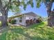 Exterior view of the rear of the home showcasing mature trees, well-maintained lawn and lots of windows at 4836 Alamo Ct, New Port Richey, FL 34655