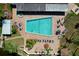 Aerial view of the community pool, highlighting lounge areas, lush landscaping, and clear blue water at 4836 Alamo Ct, New Port Richey, FL 34655