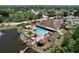 A beautiful aerial view of a community pool surrounded by palm trees next to a lake with fountain at 4836 Alamo Ct, New Port Richey, FL 34655