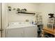 Functional laundry room with white washer and dryer, storage shelves, and tile flooring at 5092 Roble Ave, Spring Hill, FL 34608