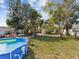 View of backyard with above ground pool, mature trees, and partial shade at 6329 Alaska Ave, New Port Richey, FL 34653