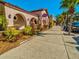 Sidewalk view of a pink-stucco building with arched walkways and lush landscaping on a bright day at 6329 Alaska Ave, New Port Richey, FL 34653