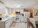 Eat in kitchen features white cabinets, stainless steel microwave and white appliances at 6329 Alaska Ave, New Port Richey, FL 34653