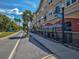 Charming building featuring commercial space with outdoor seating, complemented by beautiful palm trees and a bright blue sky at 6329 Alaska Ave, New Port Richey, FL 34653