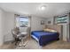 Bright bedroom with a blue quilt, two windows, and neutral decor at 6335 Kings Ct, New Port Richey, FL 34653